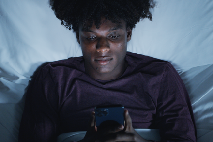 A person lying awake in bed, staring at the ceiling, in a dimly lit room.