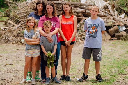 A mother of five standing in front of the remains of her flood-damaged cabin.