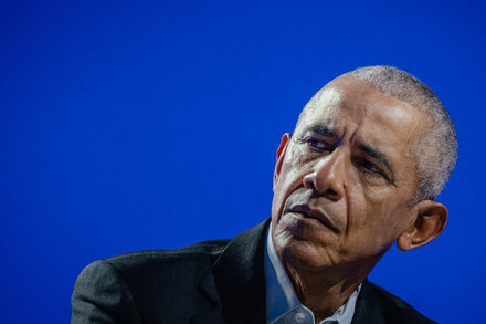 Former President Barack Obama speaks at a Democratic Party fundraising event, looking serious and engaged.