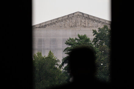 The Supreme Court building in Washington D.C., a grand neoclassical structure, stands under a clear sky. Its columns and steps are prominent, symbolizing justice and power.