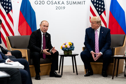 Donald Trump with Vladimir Putin, both looking serious, against a backdrop that suggests a formal meeting setting.