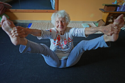 102-year-old yoga teacher standing in a yoga pose, smiling warmly, demonstrating vitality and well-being
