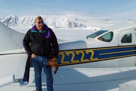 A small plane sitting on a snowy Alaskan runway, with a cooler visible inside the cockpit, referencing an incident where a plane was seized over illicit beer cargo.