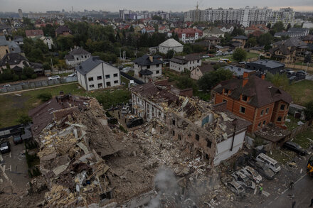 Un edificio residencial en Kiev con daños visibles por el ataque. Un agujero grande y escombros se ven en un lado. Servicios de emergencia están en el lugar.