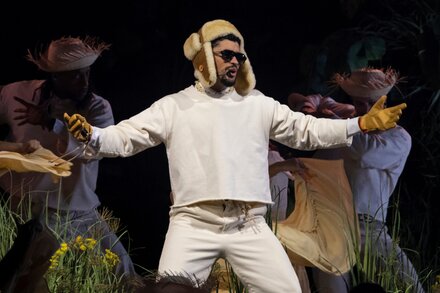 Bad Bunny actuando en el escenario con luces brillantes, representando su participación en el medio tiempo del Super Bowl.