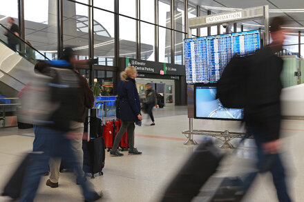 A traveler uses a biometric facial recognition scanner at an airport security checkpoint.