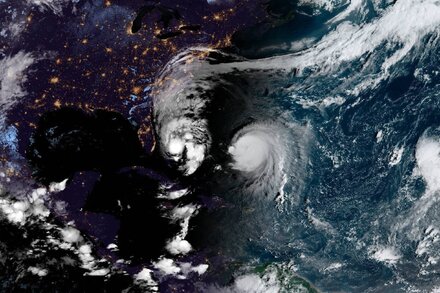 A weather map showing two large hurricane symbols approaching the eastern seaboard of the United States. One storm is positioned off the coast of Florida, and the other is further north, off the coast of the Carolinas.