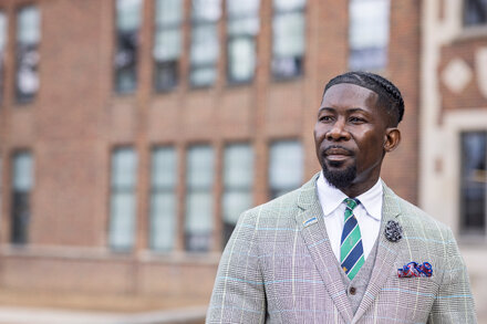 Des Moines Schools Superintendent stands in front of a school building, looking concerned after being arrested by ICE.