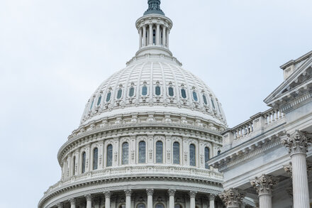 Federal workers gather outside a government building, looking concerned, as a sign hints at a looming shutdown.