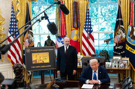 Donald Trump signing an executive order on H-1B visas in the Oval Office, surrounded by advisors.