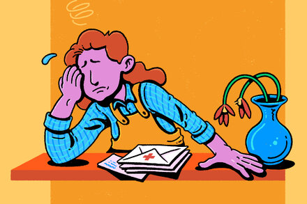 A person looking stressed while reviewing documents, possibly health insurance forms, with a calculator and a pen on a desk.