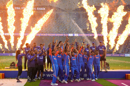 A wide shot of a cricket stadium filled with fans, with two players shaking hands on the pitch under stadium lights, symbolizing sportsmanship amidst tension.