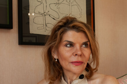 Ivana Lowell, a Guinness heiress, smiling at the camera. She is wearing a patterned top and has short hair. The image promotes her story about going to Netflix.