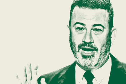 Jimmy Kimmel stands on stage, looking thoughtful, with a microphone in front of him.