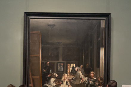 Visitors intently studying Diego Velázquez's painting 'Las Meninas' in a museum gallery, emphasizing the slow looking approach.
