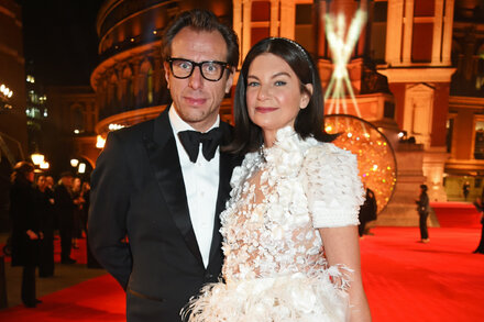 Natalie Massenet, founder of Net-a-Porter, in an elegant black dress, smiling against a stylish backdrop, representing a successful fashion entrepreneur.