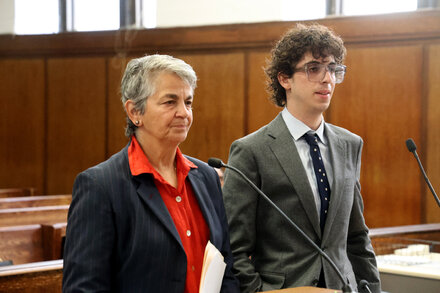 Michael Chabon's son, standing in a courthouse, looks forward with a serious expression, flanked by legal counsel after his rape charge dismissal.
