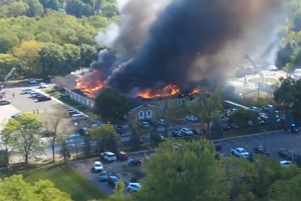 Mormon church engulfed in flames at night with emergency vehicles and smoke visible.