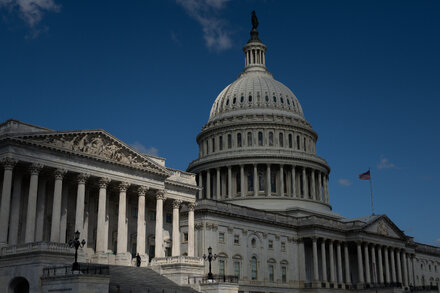 Democratic and Republican leaders in the U.S. Congress look concerned during a budget negotiation, with the Capitol building in the background.