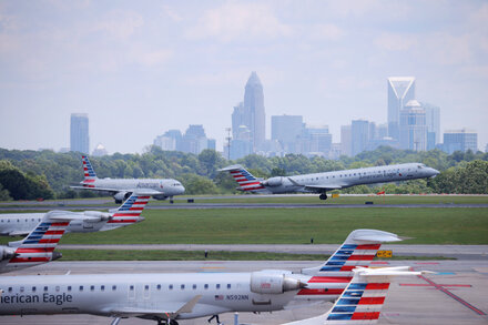An American Airlines jet on a runway at an airport, with emergency vehicles and personnel visible near the aircraft's landing gear.