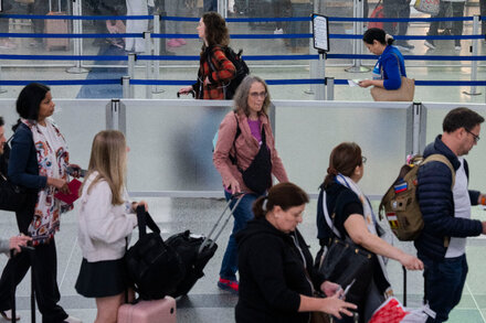 A passenger looking at an airport departure board with many flights delayed or canceled, overlaid with text 'Government Shutdown.'