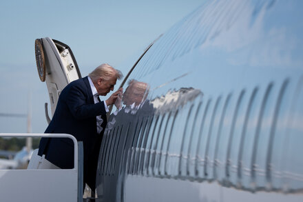 Donald Trump with a stern expression, speaking at a podium with the Seal of the President of the United States visible.