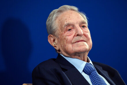 Donald Trump with a blurred image of George Soros in the background, symbolizing the article's focus on Trump's targeting of Soros's foundation.