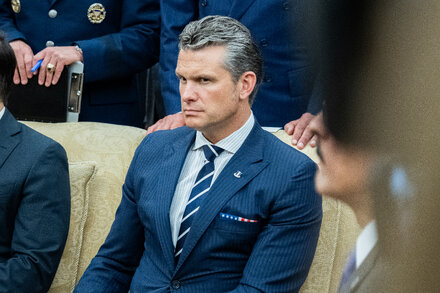 U.S. military officers in uniform, seated in an auditorium, listening intently to a speaker. The image conveys a formal and attentive atmosphere.
