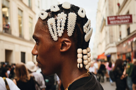 Person walking on a city street, showcasing stylish accessories like a handbag, sunglasses, and jewelry. The image captures a candid street fashion moment.