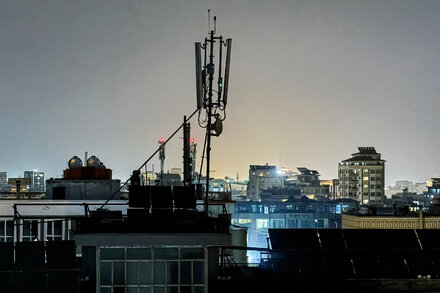 A person using a smartphone in Afghanistan, against a backdrop that suggests limited connectivity or a network issue. The image should convey the difficulty or inability to access the internet.