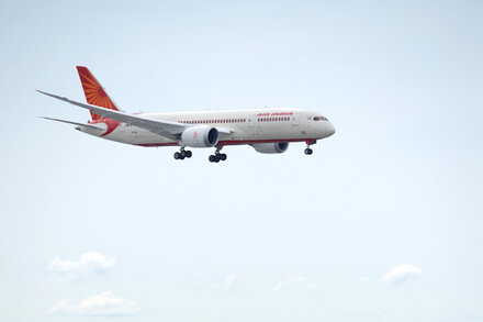 Air India Boeing 787 Dreamliner aircraft parked on a tarmac, with a pilot's silhouette visible in the cockpit.