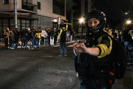 Federal agents in tactical gear stand in front of a federal courthouse in Portland, Oregon, with smoke in the background.