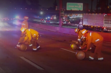 Damaged truck with beer kegs and cans spilled across a California freeway after a crash, causing traffic delays.