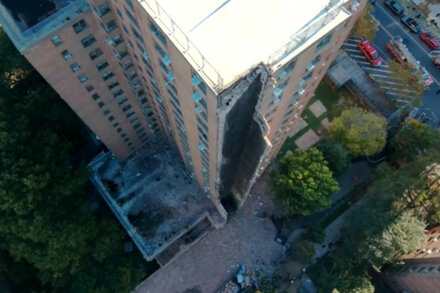 Rescue workers and emergency vehicles surround a partially collapsed 20-story apartment building in the Bronx, with debris visible.