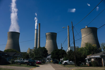 Smoke billows from the tops of several large cooling towers at a coal-fired power plant.