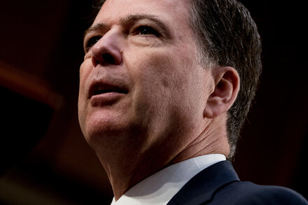 Close-up of James Comey, former FBI director, looking serious, with a subtle alert icon superimposed, symbolizing a danger signal.