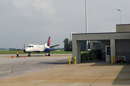 An airport control tower with planes on the tarmac, illustrating potential impact of government shutdown on commercial aviation.