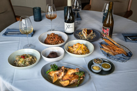 An elegantly set table at OfCorsica! restaurant, with a focus on fresh ingredients and a Mediterranean aesthetic.