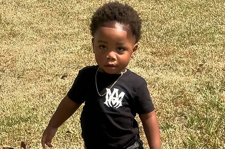Police investigate a day care center where dogs reportedly killed a 2-year-old. The image shows an exterior view of a residential-looking building with police tape or vehicles visible, conveying a sense of tragedy and law enforcement presence.