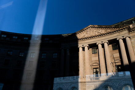 EPA employees continue working at their desks despite a government shutdown plan that called for furloughs, with a sign indicating the building is the William Jefferson Clinton Federal Building.