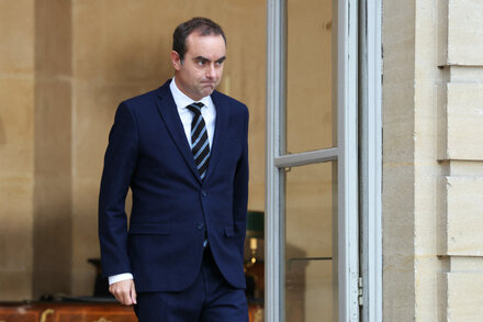 French Prime Minister Gabriel Attal walking out of Élysée Palace after resigning, a serious expression on his face.
