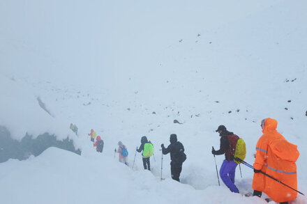 Hundreds of hikers stranded on a snowy Mount Everest during a severe snowstorm, with climbers huddled together for warmth and rescue helicopters attempting to navigate the treacherous conditions.