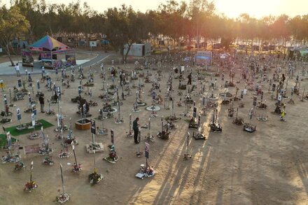 An aerial view shows a protest in Israel, with a large crowd of people gathered in a public square, some holding flags or signs. The image conveys a sense of turmoil and internal conflict.