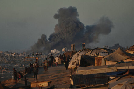 Smoke rises over buildings in Gaza following an Israeli airstrike, with damaged structures visible.
