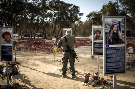 A woman lights a candle in front of a memorial wall in Israel, marking a somber two-year milestone.