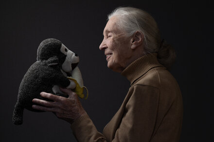 Jane Goodall, renowned primatologist and conservationist, smiling gently while standing in a natural setting.