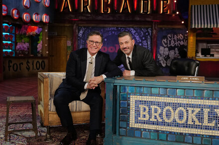 Jimmy Kimmel and Stephen Colbert stand together on stage, smiling warmly at each other in a show of unity during a joint appearance in New York.