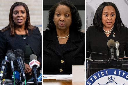 Letitia James, New York Attorney General, stands in front of a microphone, looking serious. She is a Black woman with short, dark hair, wearing a dark suit jacket and a white blouse.