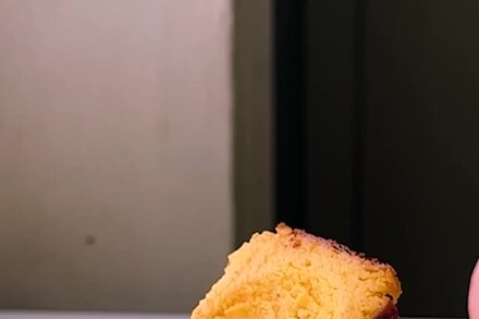 A close-up of a golden-brown mango Basque cheesecake with a creamy, slightly burnt top, garnished with fresh mango slices.