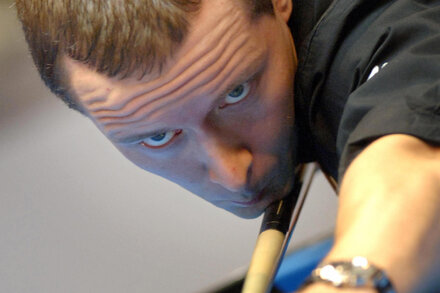 Mika Immonen, the Finnish pool player known as 'The Iceman,' stands by a pool table holding a cue stick, looking intently at the ball.